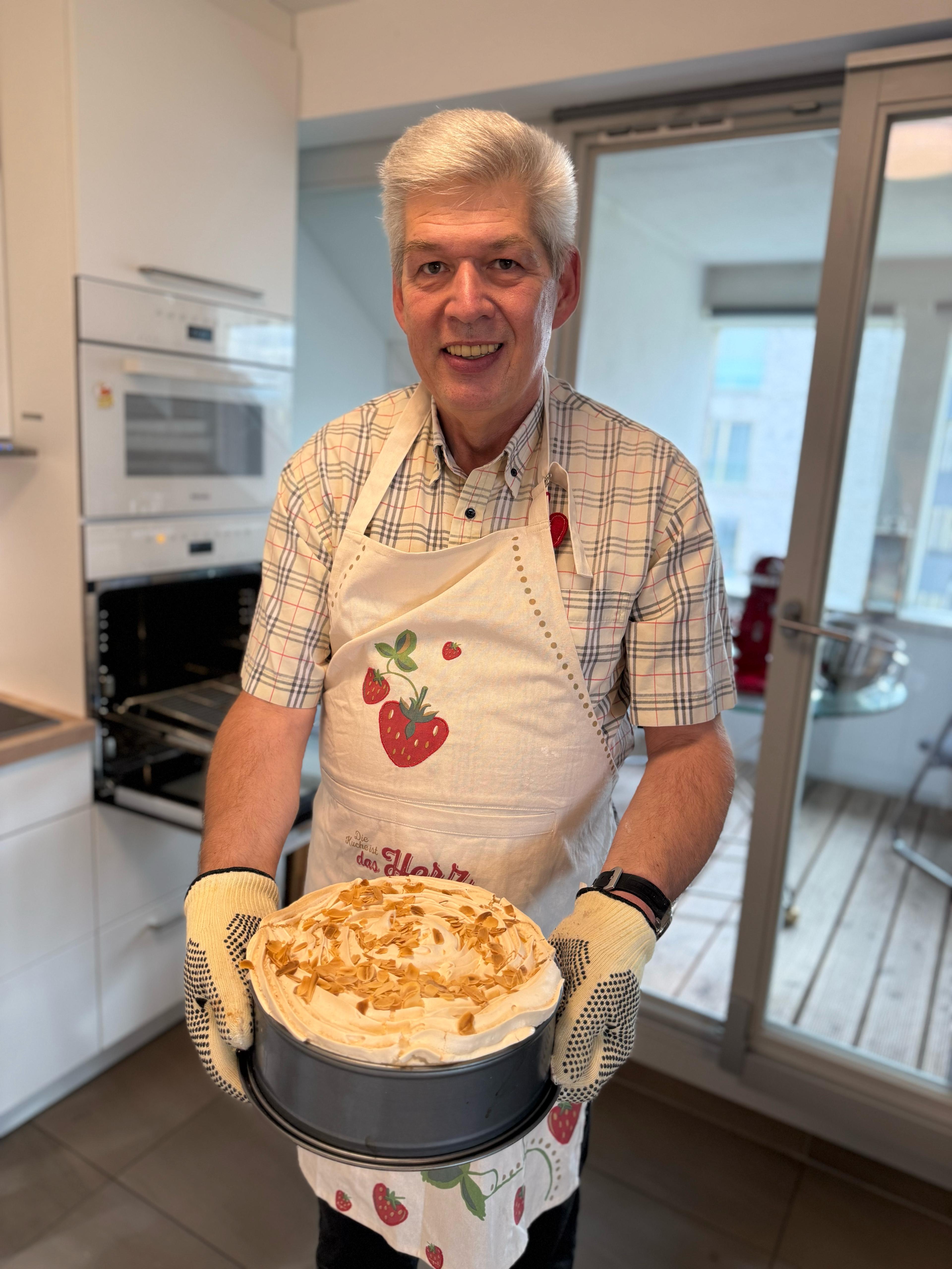 Eine Person in einer Küche hält Apfel-Rhabarber Baiserkuchen